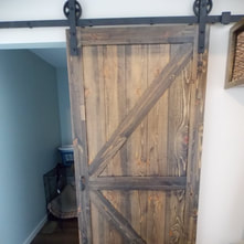 Wood barn doors are a popular way to create a rustic home style. We can build custom wood barn doors to fit any space and match any home style. We build barn doors out of all types of wood, and using a wide variety of different types of barn door hardware. This barn door was built for a homeowner in Maple Grove, MN.